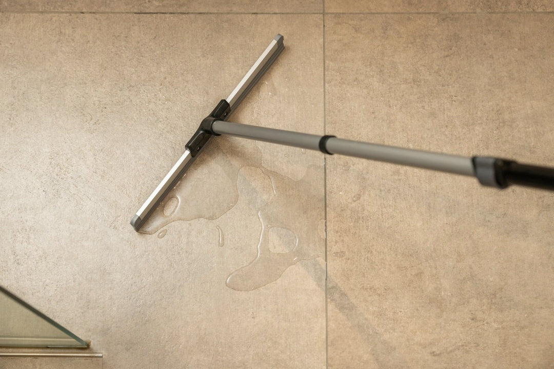 Floor squeegee wiping water off a tiled floor