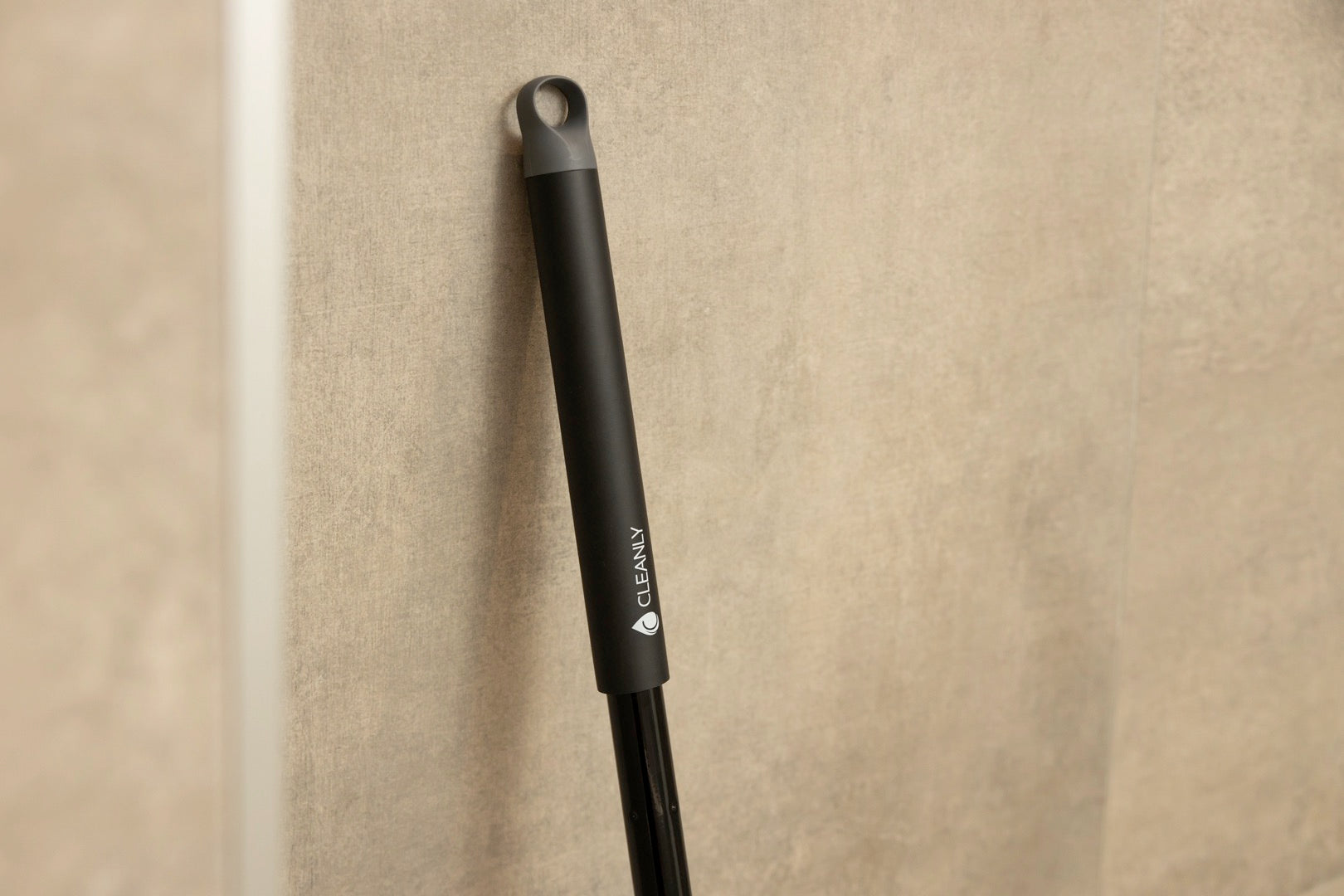 Cleanly-branded black handle leaning against a beige wall