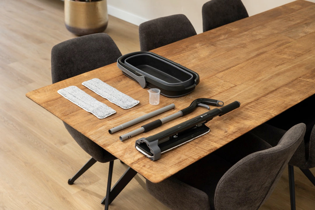 Disassembled floor mop set with spray function and cleaning pads laid out on a wooden table