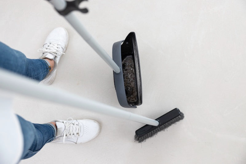 A top-down view of the cleanly broom and dustpan with a closed, foldable design, showing how it securely holds debris without spilling