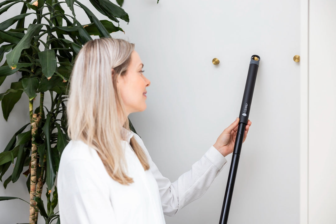 Woman hanging a Cleanly branded telescopic pole on a wall hook